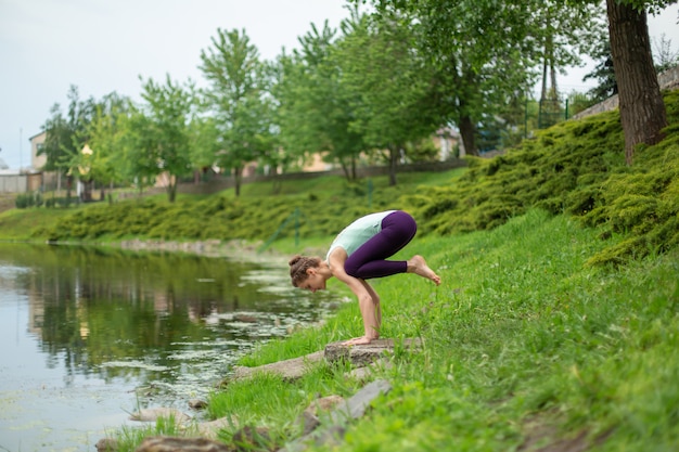 Joven hermosa chica morena caucásica haciendo yoga en un césped verde