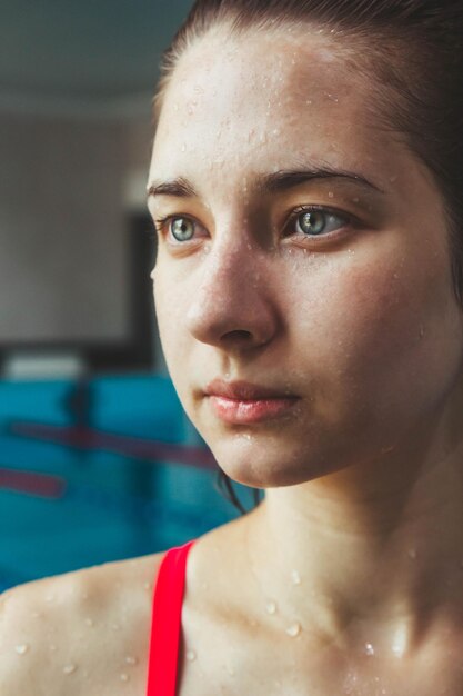 Joven hermosa chica morena en el fondo de la piscina Retrato de una niña cerca del lado de la piscina Natación estilo de vida saludable