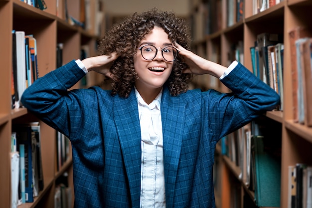 Joven hermosa chica rizada en gafas y un traje azul