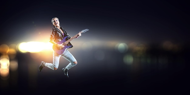 Joven y hermosa chica rockera tocando la guitarra eléctrica. Técnica mixta