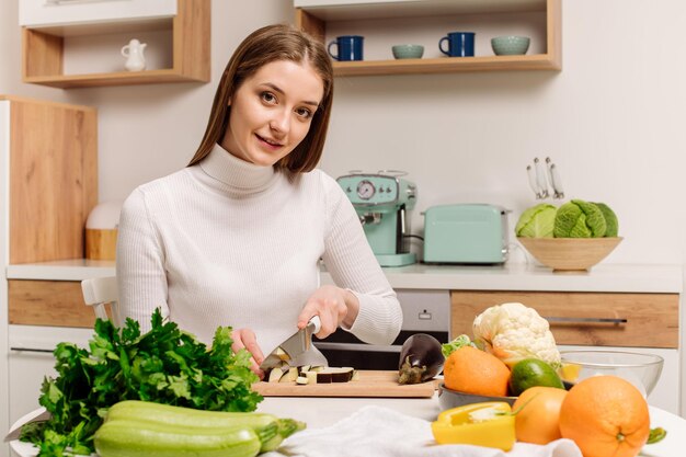 Una joven y hermosa chica vegetariana o bloguera prepara el desayuno de frutas, verduras y verduras en casa en la cocina Blog sobre alimentación saludable