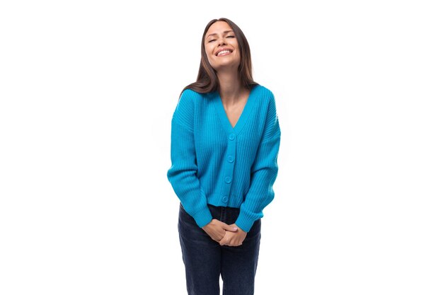 Foto joven hermosa y delgada mujer morena europea vestida con un cardigan azul con botones en un blanco