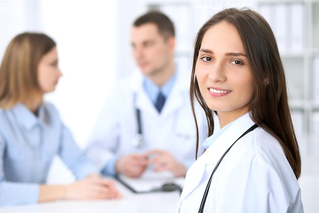 Una joven y hermosa doctora sonriendo al fondo con un paciente en el hospital. Concepto de servicio médico de alto nivel y calidad.