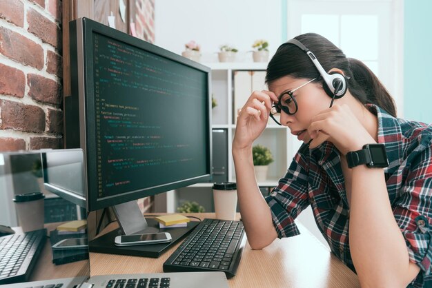 una joven y hermosa empleada operadora recibe un teléfono de quejas de clientes sobre el sitio web en línea roto y ella tiene dolor de cabeza y se siente cansada.