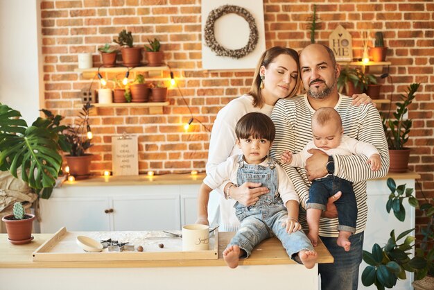 Joven hermosa familia divirtiéndose y cocinando en la soleada cocina