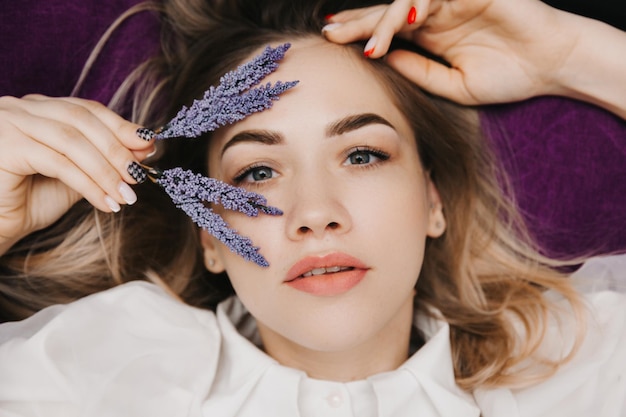 Una joven hermosa con una flor se encuentra en el fondo Retrato de niña de belleza de concepto de cuidado de la piel