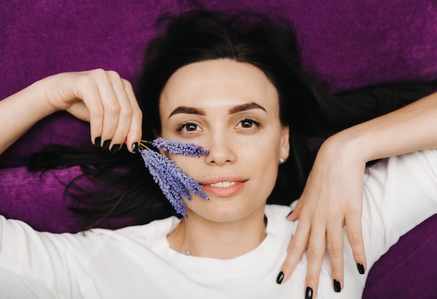 Foto una joven hermosa con una flor se encuentra en el fondo retrato de niña de belleza de concepto de cuidado de la piel