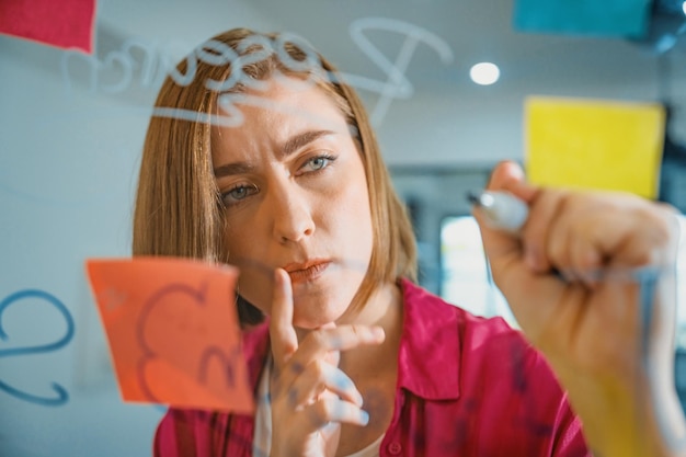 Foto joven y hermosa líder de negocios escribiendo una idea de marketing a bordo de la inmaculada.