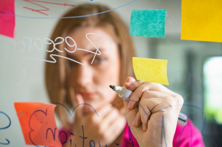 Foto joven y hermosa líder de negocios escribiendo una idea de marketing a bordo de la inmaculada