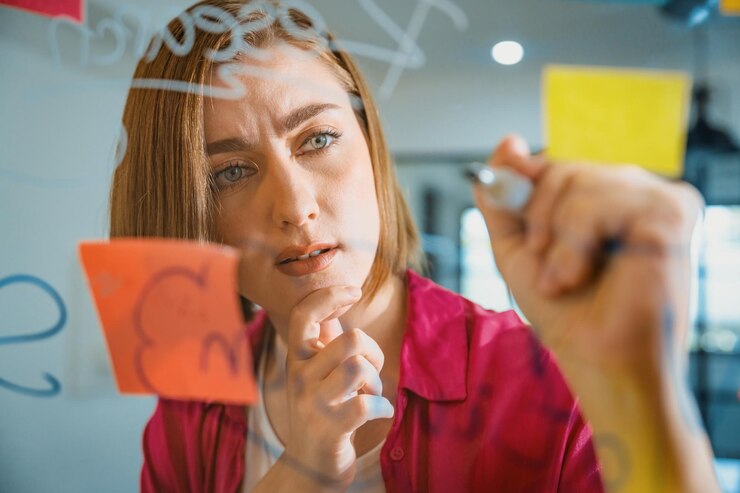 Foto joven y hermosa líder de negocios escribiendo una idea de marketing a bordo inmaculada