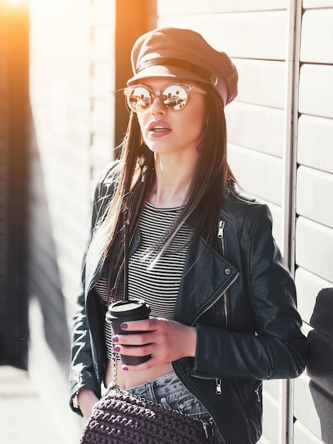 Joven hermosa morena bebiendo café caminando por la ciudad