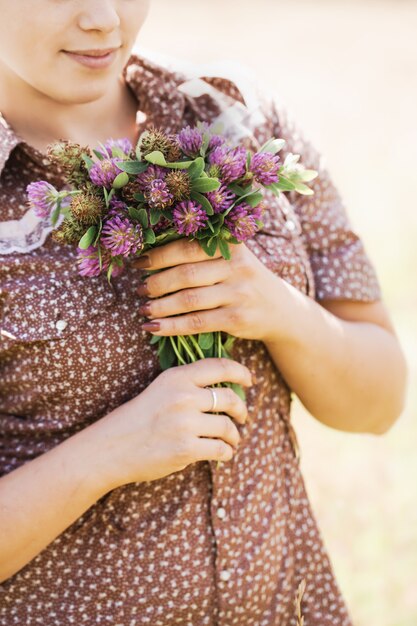 Joven hermosa morena con trenza en la cabeza con un vestido de estilo campestre en el campo