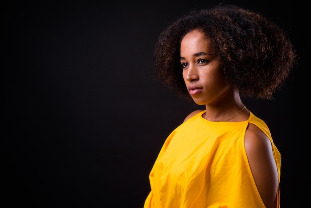 Joven hermosa mujer africana con cabello afro sobre negro