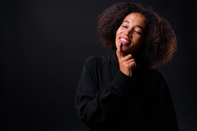 Joven hermosa mujer africana con cabello afro sobre negro