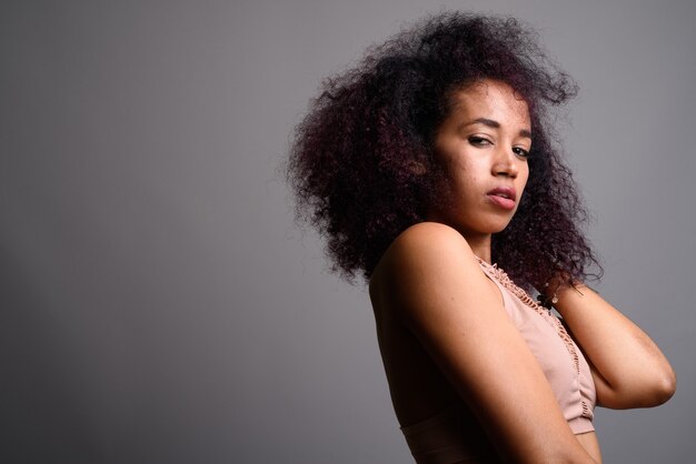 Joven hermosa mujer africana contra la pared gris