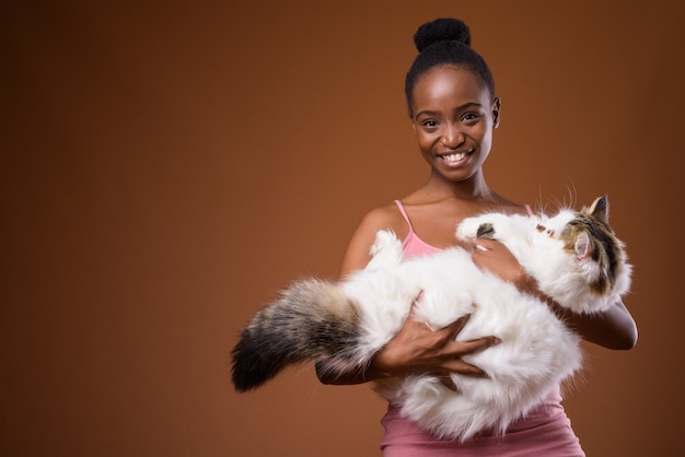 Joven hermosa mujer africana Zulú sosteniendo gato mientras sonríe