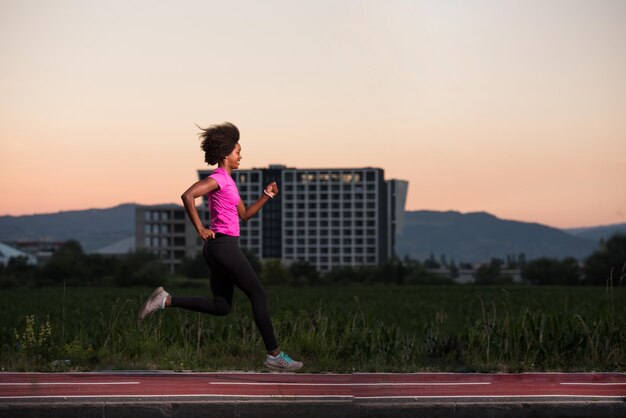 joven hermosa mujer afroamericana disfruta corriendo afuera de la hermosa noche de verano en la ciudad