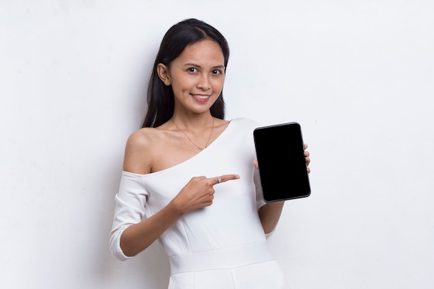 Joven hermosa mujer asiática demostrando teléfono celular móvil aislado sobre fondo blanco.