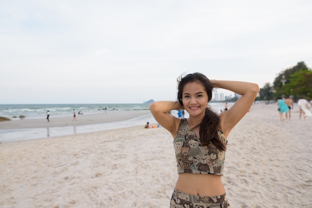 Joven hermosa mujer asiática feliz sonriendo mientras sostiene su cabello