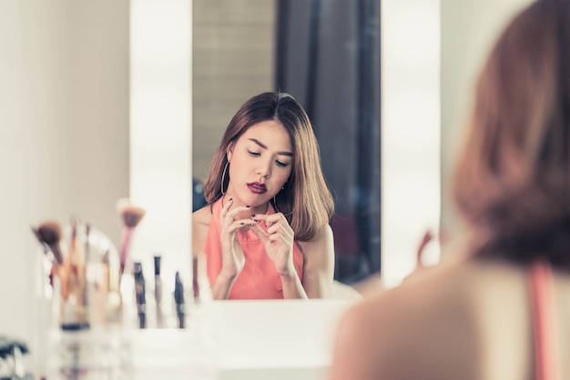 Joven hermosa mujer asiática haciendo maquillaje cerca de espejo