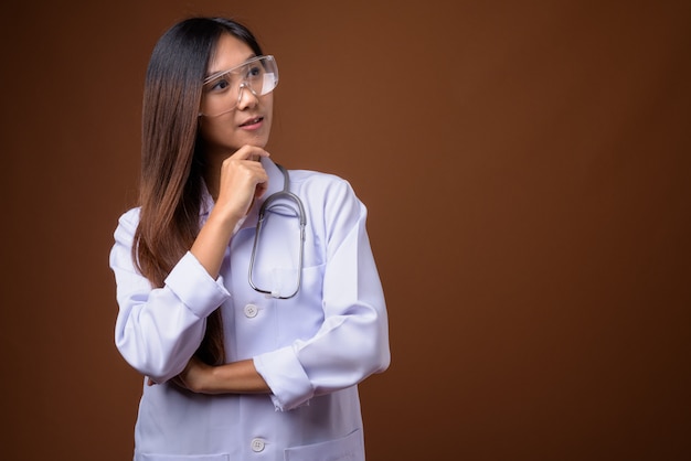 Joven hermosa mujer asiática médico con gafas protectoras ag