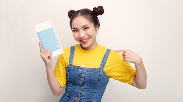 Joven hermosa mujer asiática con pasaporte sonriendo feliz señalando con la mano y el dedo