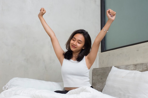 Foto joven hermosa mujer asiática que se estira feliz y relajada después de despertarse se siente fresca en casa