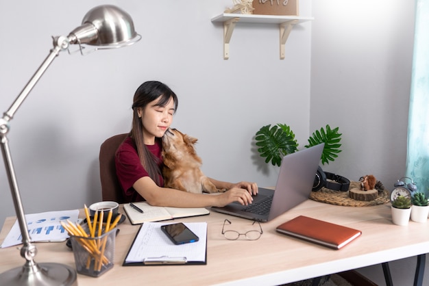 Joven hermosa mujer asiática trabajando en casa con su mascota