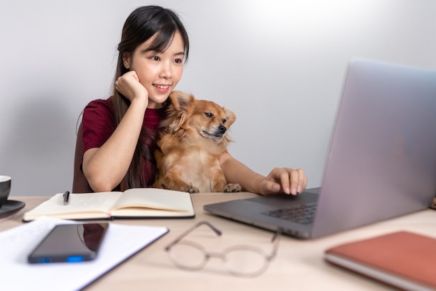 Joven hermosa mujer asiática trabajando en casa con su mascota