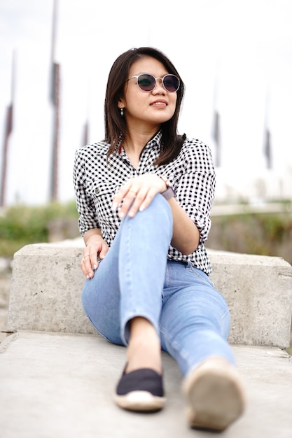 Joven hermosa mujer asiática vestida con camisa a cuadros y pantalones vaqueros azules posando al aire libre