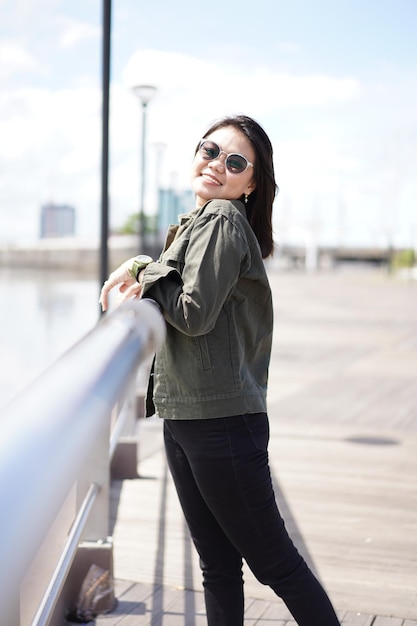 Joven hermosa mujer asiática vestida con chaqueta y jeans negros posando al aire libre