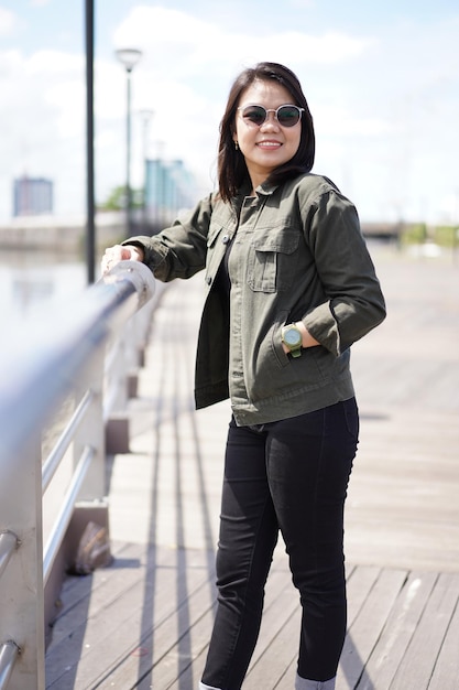 Joven hermosa mujer asiática vestida con chaqueta y jeans negros posando al aire libre