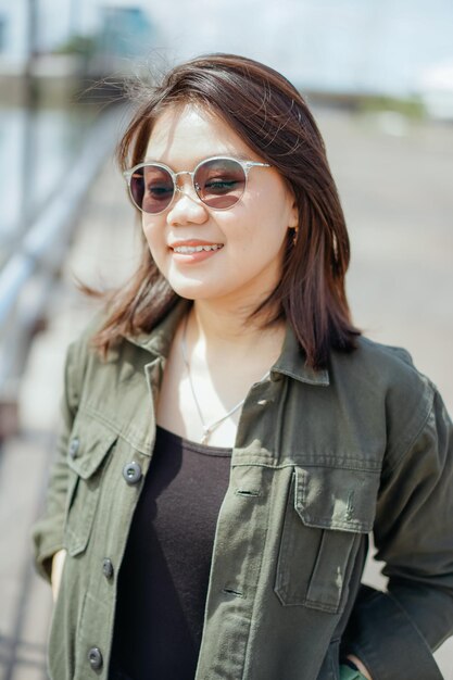 Joven hermosa mujer asiática vestida con chaqueta y jeans negros posando al aire libre