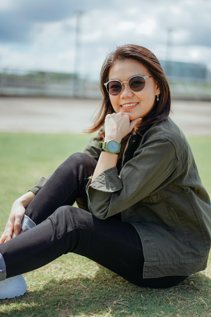 Joven hermosa mujer asiática vestida con chaqueta y jeans negros posando al aire libre