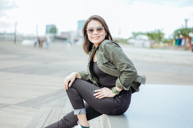 Joven hermosa mujer asiática vestida con chaqueta y jeans negros posando al aire libre