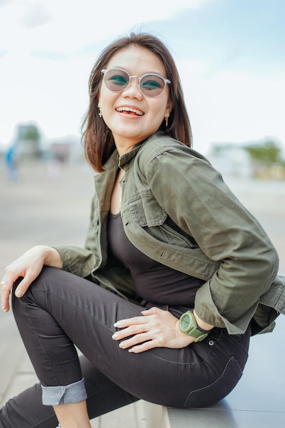 Joven hermosa mujer asiática vestida con chaqueta y jeans negros posando al aire libre