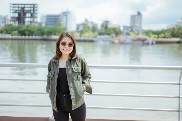 Joven hermosa mujer asiática vestida con chaqueta y jeans negros posando al aire libre