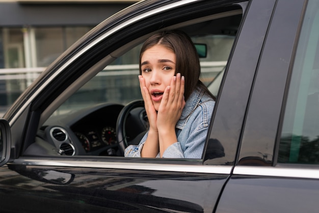 Joven hermosa mujer asustada está en el coche