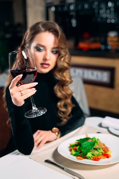 Joven hermosa mujer bebiendo vino en un restaurante.