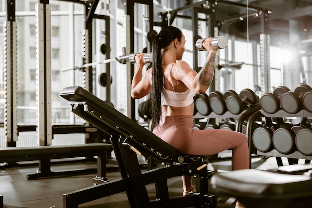 Joven hermosa mujer caucásica en forma fuerte está haciendo ejercicios en el gimnasio