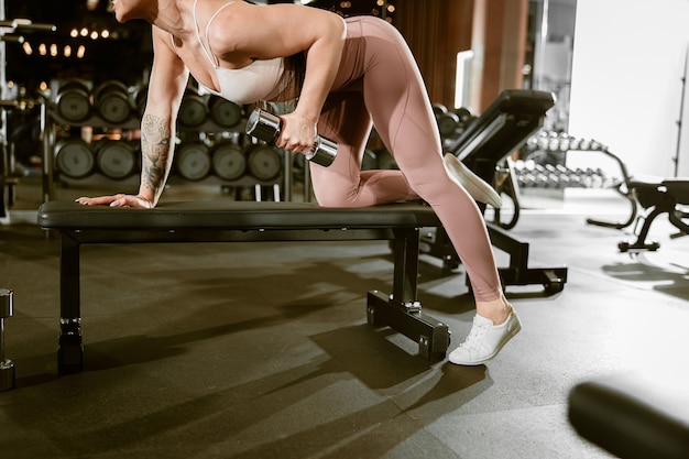 Joven hermosa mujer caucásica en forma fuerte está haciendo ejercicios en el gimnasio