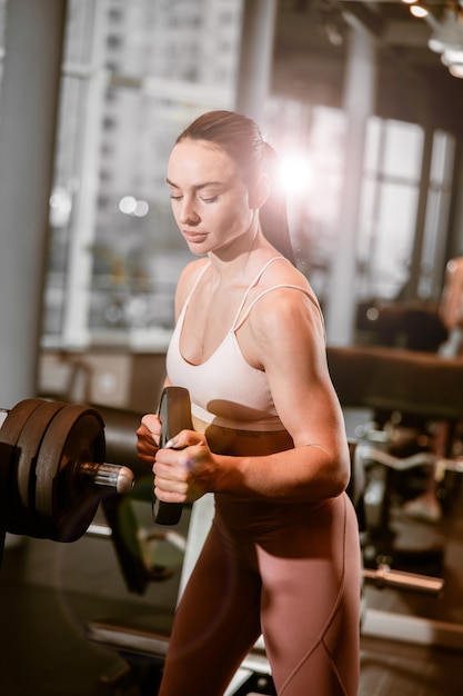 Joven hermosa mujer caucásica en forma fuerte está haciendo ejercicios en el gimnasio