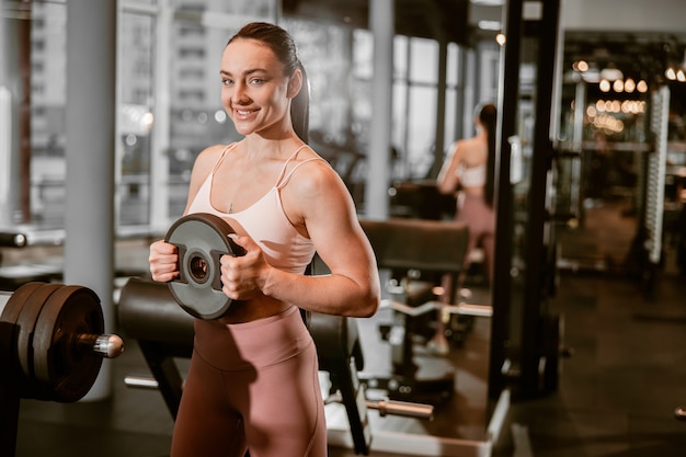 Joven hermosa mujer caucásica en forma fuerte está haciendo ejercicios en el gimnasio