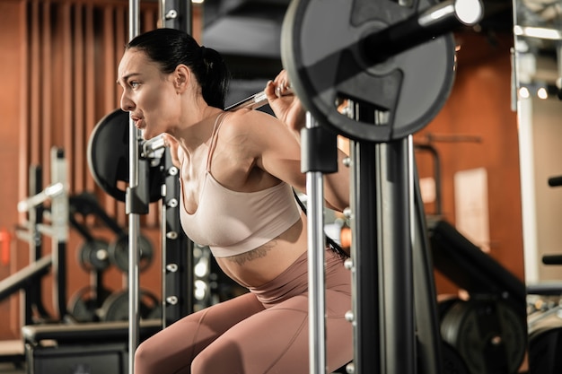 Joven hermosa mujer caucásica en forma fuerte está haciendo ejercicios en el gimnasio