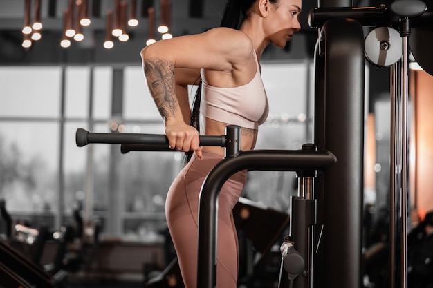 Joven hermosa mujer caucásica en forma fuerte está haciendo ejercicios en el gimnasio