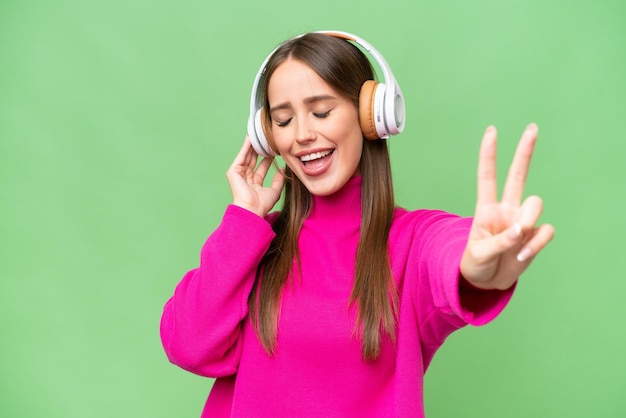 Joven hermosa mujer caucásica sobre un fondo aislado escuchando música y cantando