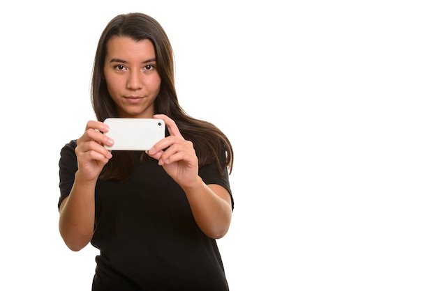 Joven hermosa mujer caucásica tomando fotografías con teléfono móvil aislado en blanco