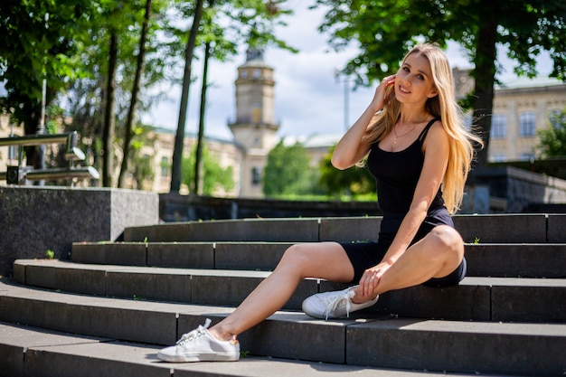 Joven hermosa mujer deportiva rubia en una camiseta sin mangas negra y en negro ajustado