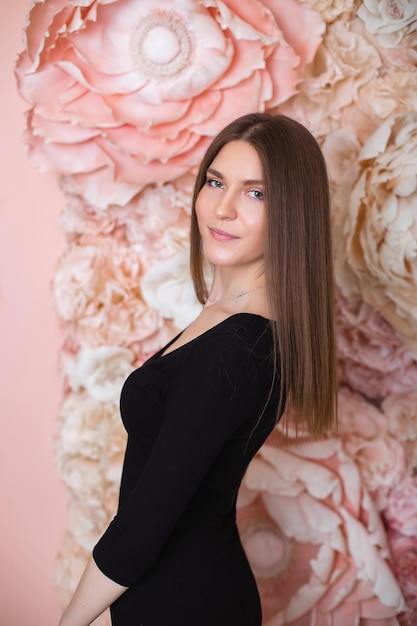 Joven hermosa mujer elegante con cabello largo morena sobre fondo de pared de flores