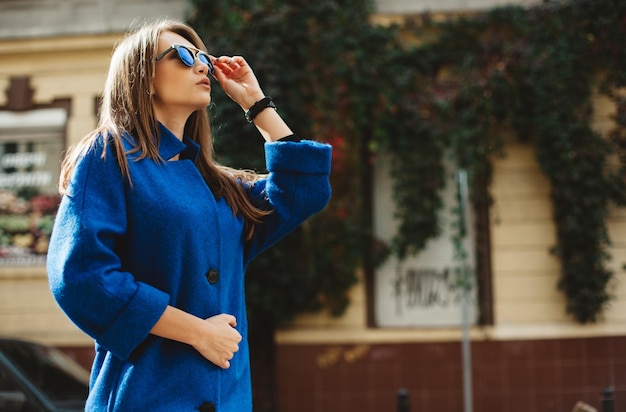 Joven hermosa mujer con estilo caminando en la calle con abrigo azul tendencia de la moda de otoño